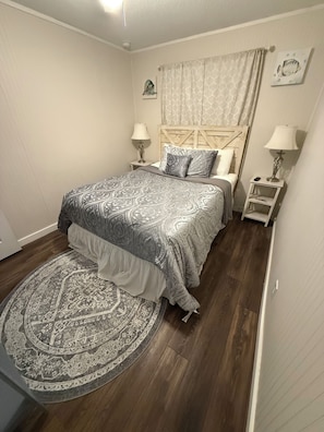 A bedroom with a bed, two bedside tables, a rug, and a headboard.