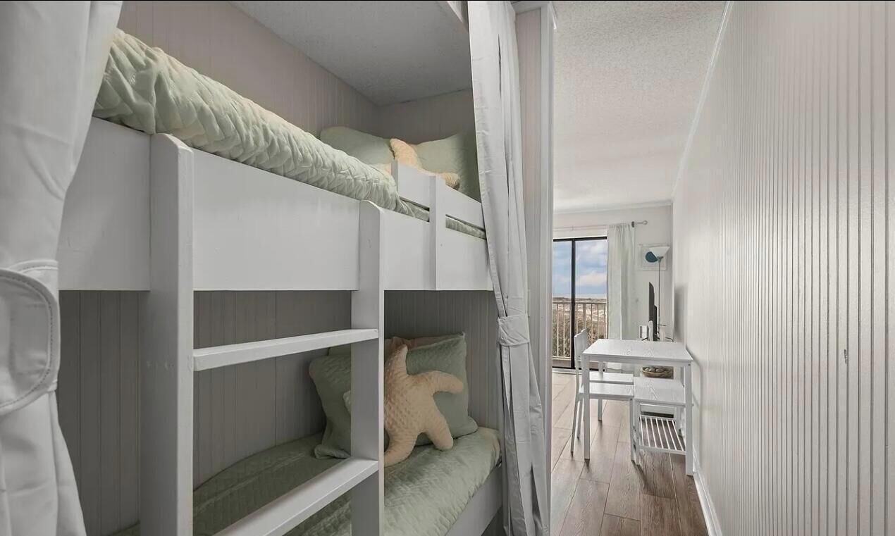 A compact room with bunk beds, a small table, and a view of the outdoors.