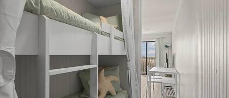 A compact room with bunk beds, a small table, and a view of the outdoors.