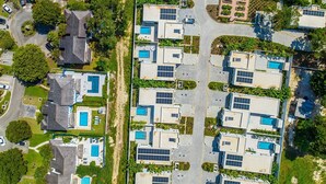 Un quartier résidentiel composé de plusieurs maisons, chacune dotée d’une piscine et de panneaux solaires.
