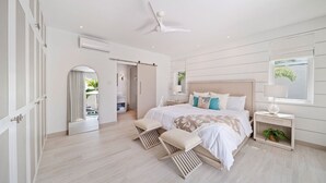 Une chambre moderne avec un grand lit, un ventilateur de plafond et une vue sur une piscine.