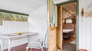 A compact room with a bed, a small table, and a chair. A wooden door leads to another room with a bed and a window. - 3 bedroom stunning home in Rødby (Rødby)