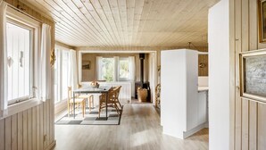 A wooden interior with a dining area, a kitchen with a wood-burning stove, and a white cabinet. - 3 bedroom stunning home in Rødby (Rødby)