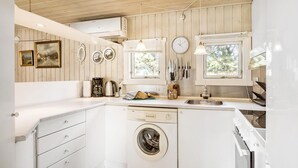 A compact kitchen with a built-in washing machine, a coffee maker, and a sink. - 3 bedroom stunning home in Rødby (Rødby)