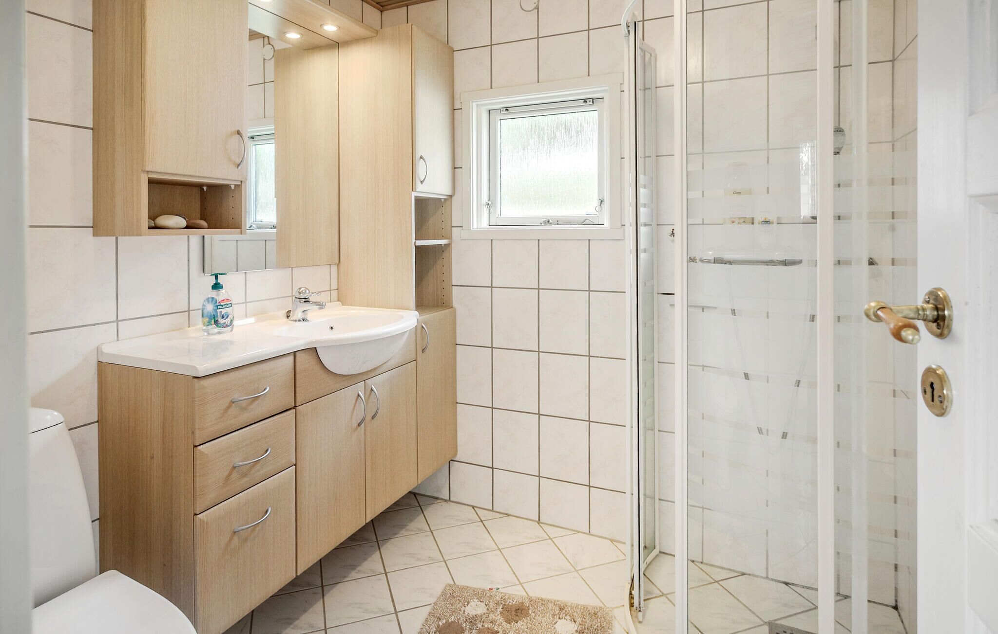 A modern bathroom with a wooden vanity, a sink, and a glass shower enclosure.
