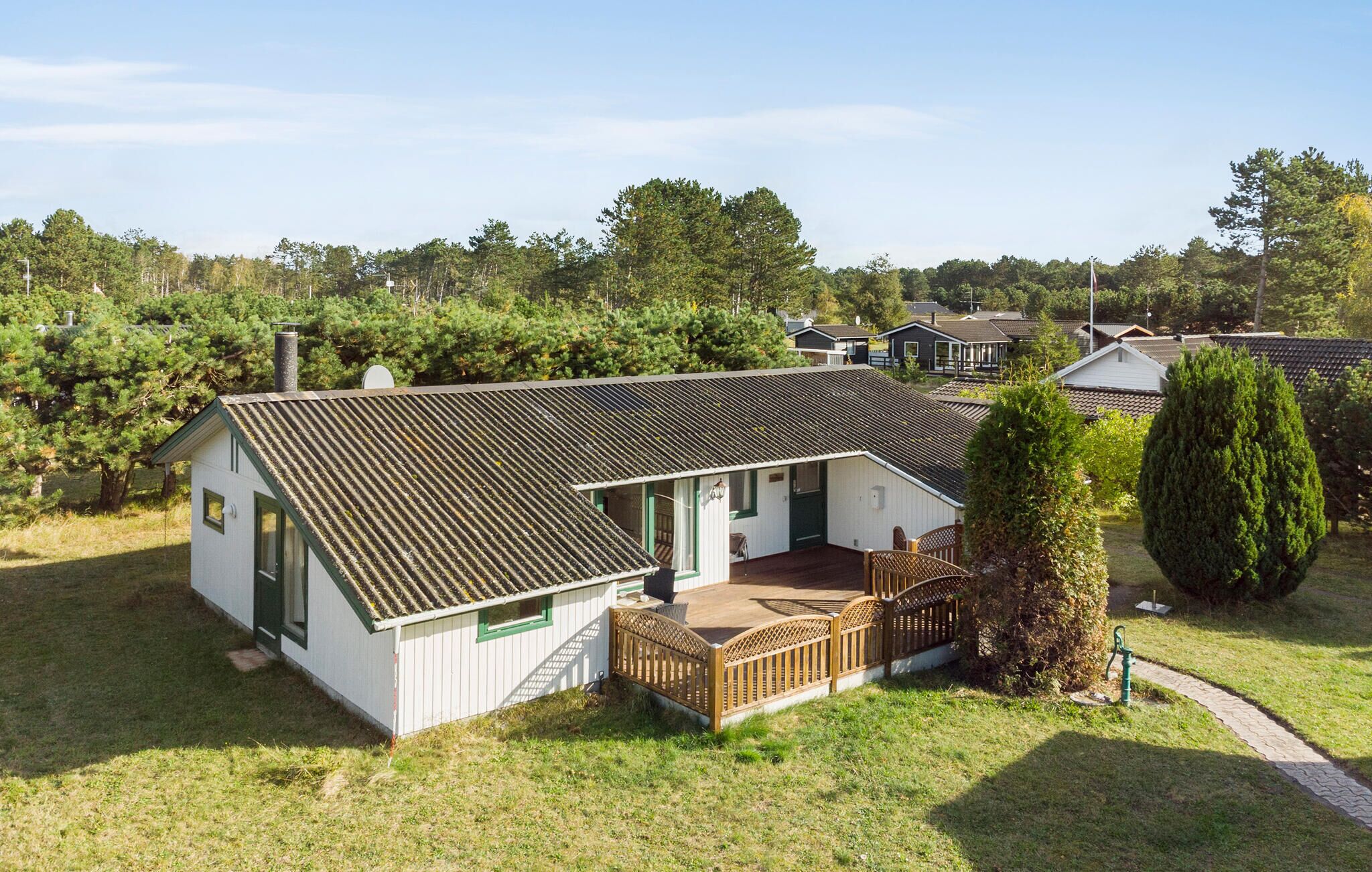 A single-story house with a sloped roof, a small porch, and a fenced yard.