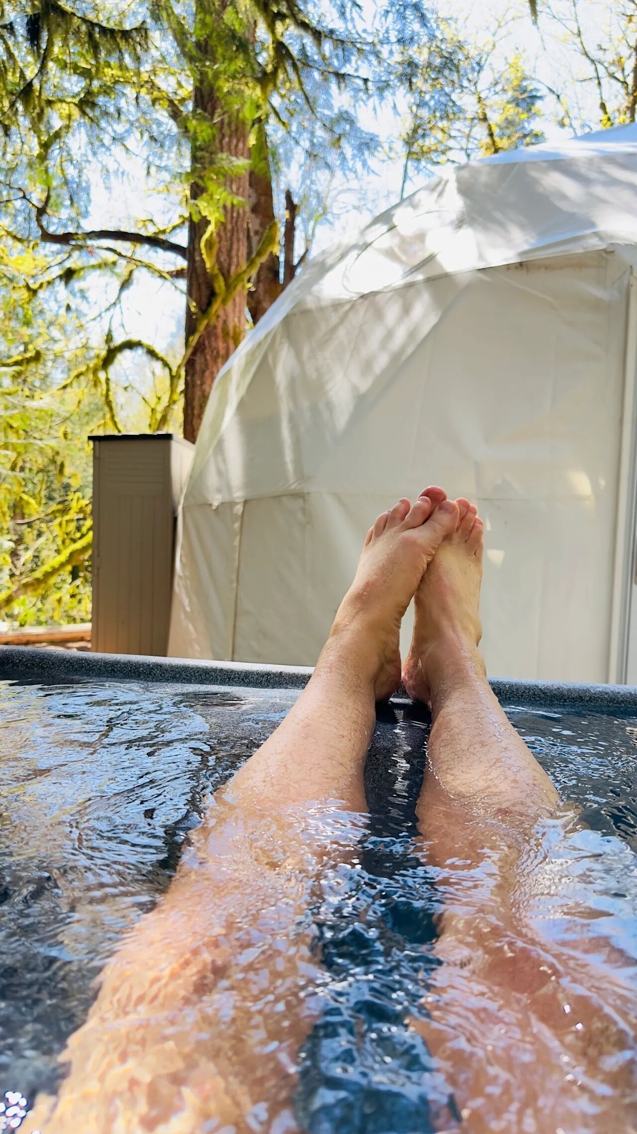 Iemand ontspant in een hottub, met een tent op de achtergrond.