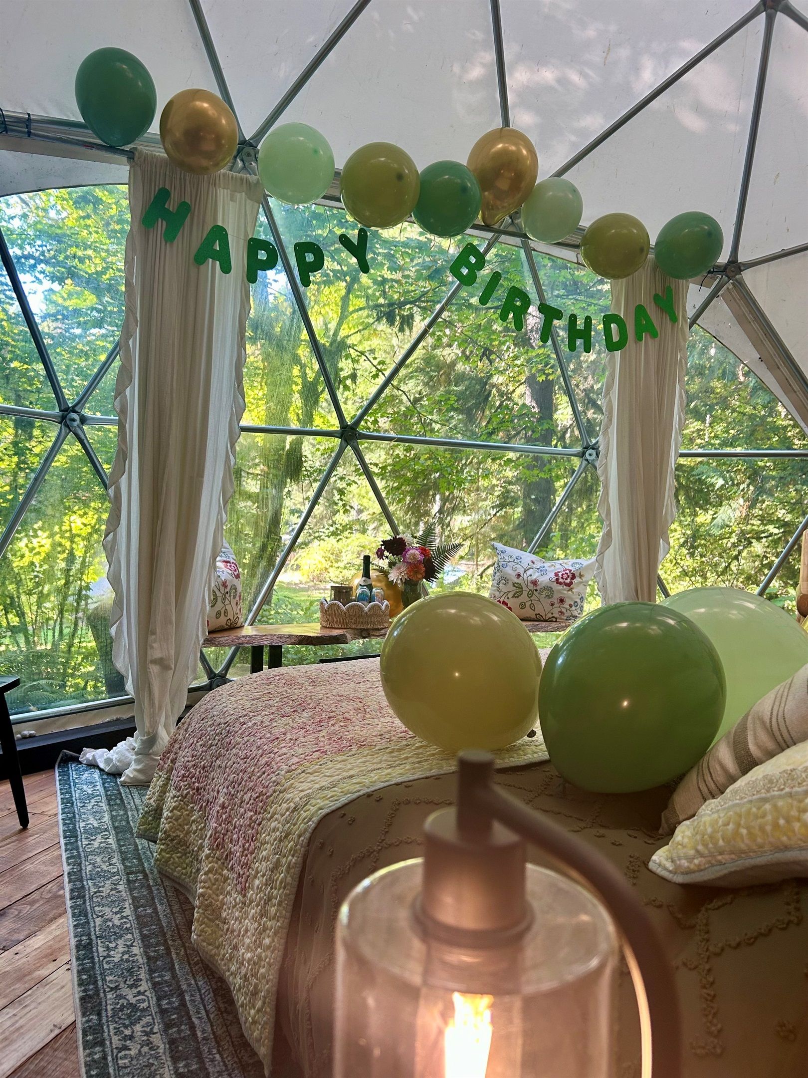 Una habitación con carpa, una cama, globos y vistas a árboles.