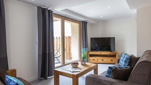 Un salon moderne comprenant un canapé, une table basse, un téléviseur et un meuble en bois.