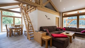 A spacious living area with a wooden staircase, a sofa set, and a dining table. - Appt + mezzanine | Vue imprenable (Peisey-Nancroix)