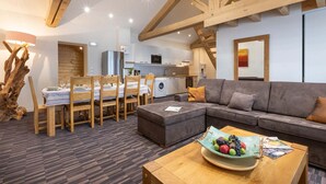 A modern living room with a grey sofa, wooden dining table, and a kitchen in the background. - Appt au calme avec vue imprenable ! (Peisey-Nancroix)
