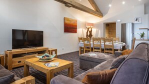 A modern living room with a flat-screen TV, wooden furniture, a dining area with a table set for four, and a kitchen area with a refrigerator. - Appt au calme avec vue imprenable ! (Peisey-Nancroix)