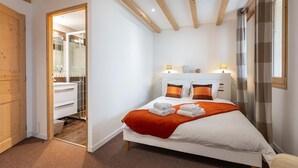 A bedroom with a bed, two bedside lamps, a window with curtains, and a wooden door leading to a bathroom. - Appt au calme avec vue imprenable ! (Peisey-Nancroix)