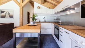 Una cucina moderna con travi in legno, mobili bianchi, piano di lavoro in legno e forno incassato.