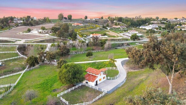An aerial view of a rural property with fenced areas, a winding road, and scattered buildings. - Modern Guesthouse on 5 Acre Estate Near Wineries (Temecula)