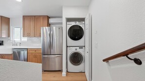 A compact kitchen with stainless steel appliances, wooden cabinets, and a built-in washer and dryer. - Modern Guesthouse on 5 Acre Estate Near Wineries (Temecula)