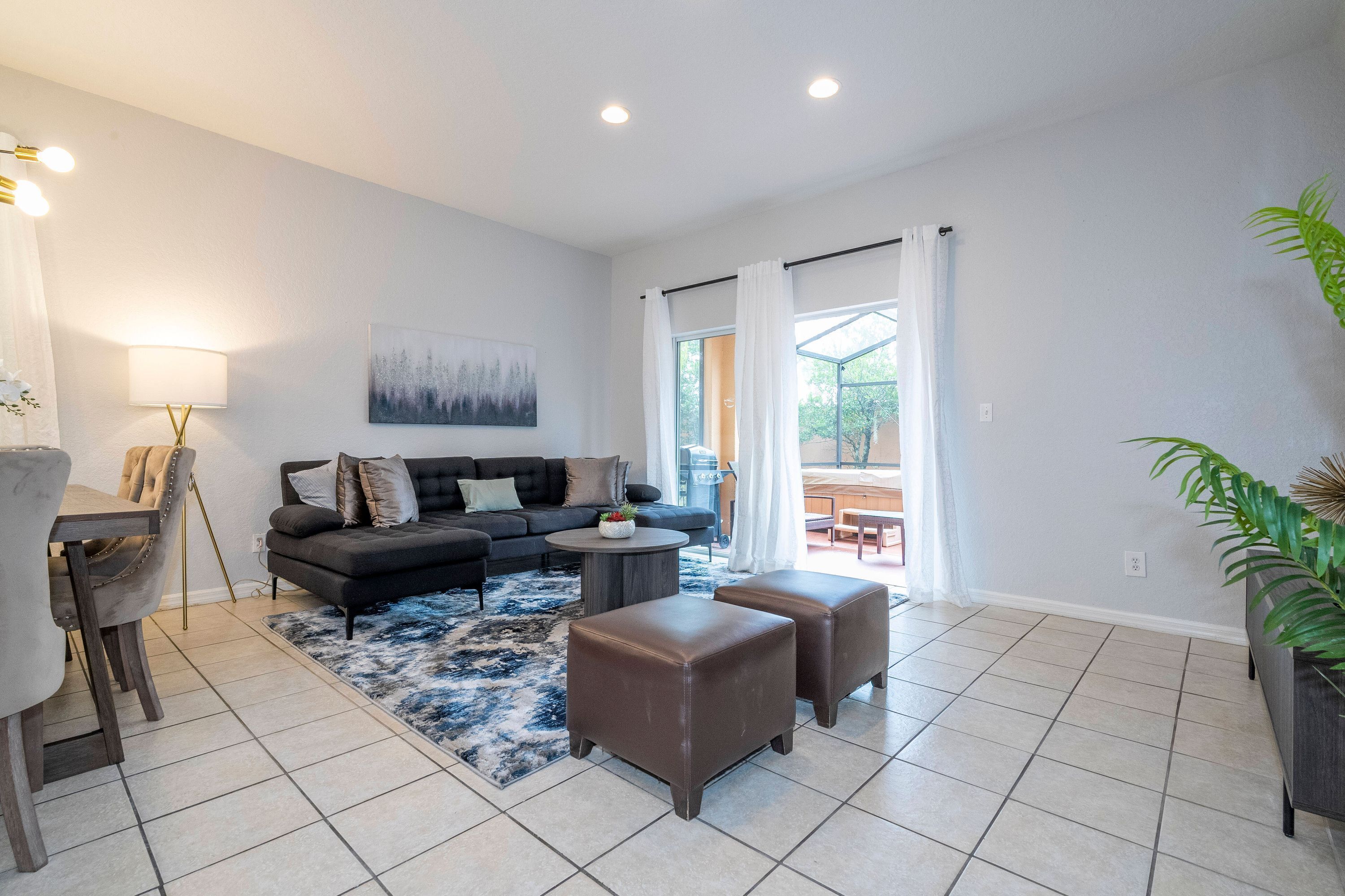 A modern living room with a sofa, ottomans, a coffee table, and a rug.
