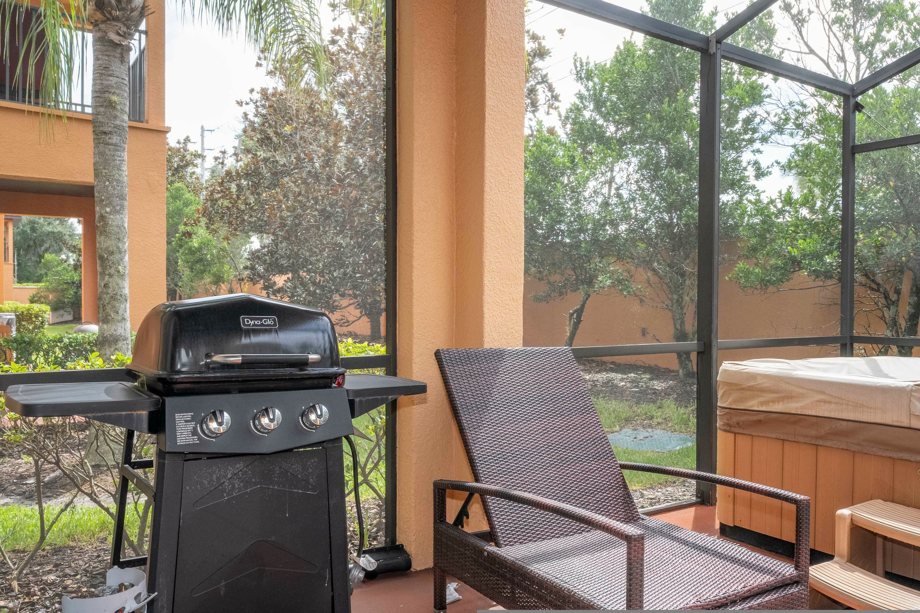 A balcony with a grill, a wicker chair, and a hot tub.