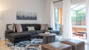 Una sala de estar moderna con un sofá modular, una mesa redonda de centro y vistas a un patio exterior.