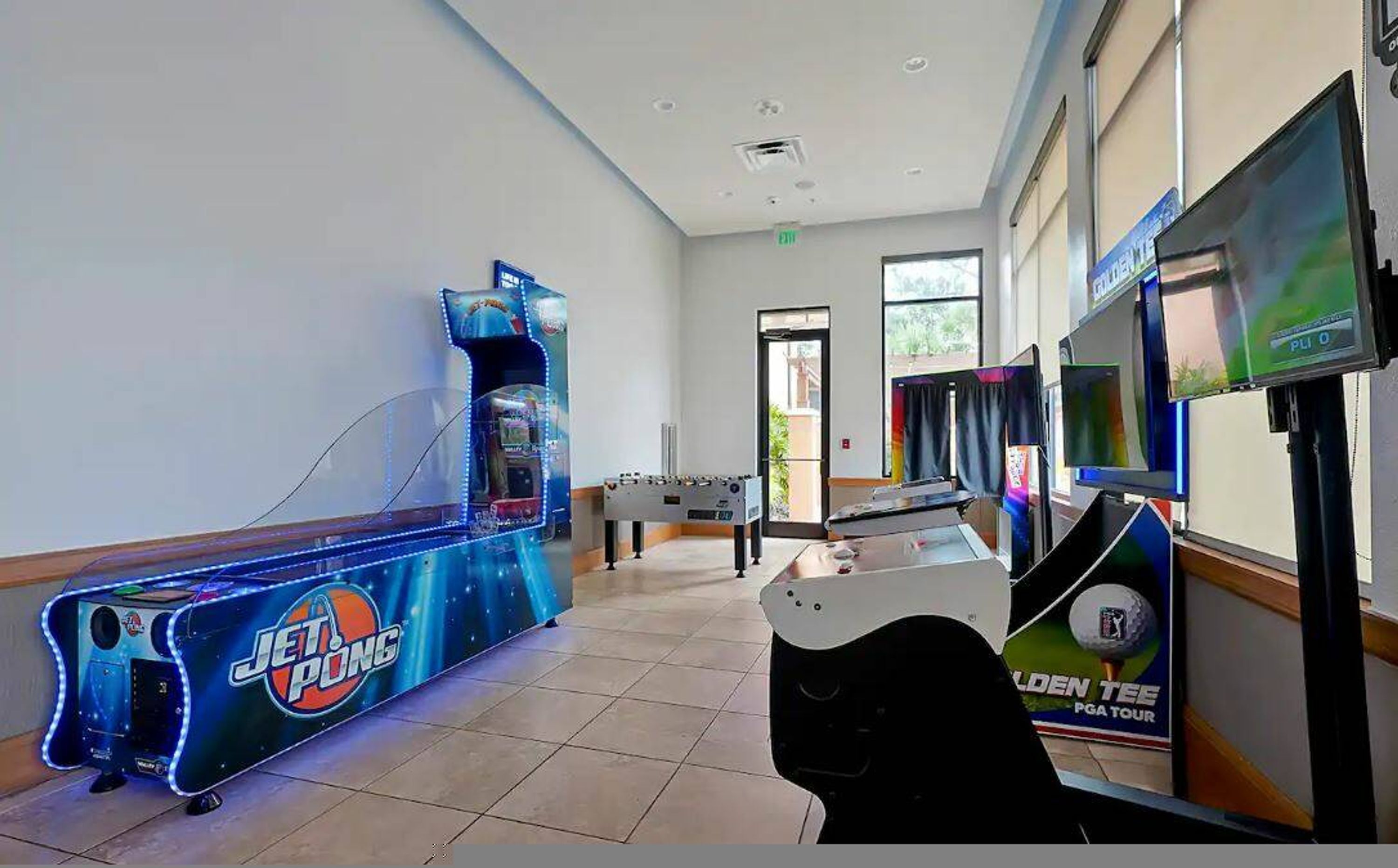 A room with a foosball table, a pool table, and a billiards table.