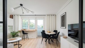 A modern kitchen with a dining area, a TV, and a large window. - Aleja Waszyngtona Deluxe Apartment (Warszawa)