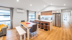 Una cocina moderna con armarios de madera, un refrigerador de acero inoxidable y una isla central con taburetes de bar.