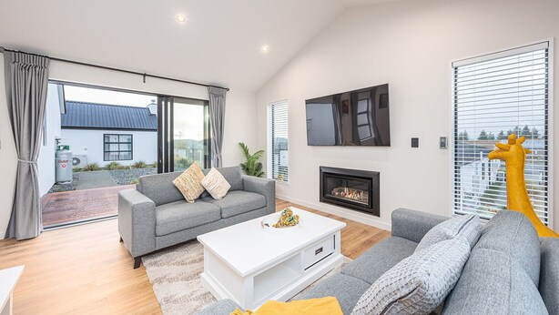 Una sala de estar moderna con un sofá gris, una mesa de centro blanca y una chimenea.