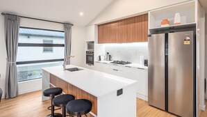 Una cocina moderna con una isla central, electrodomésticos de acero inoxidable y vistas a un edificio.