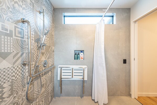 A modern bathroom with a shower, a vanity, and a window.