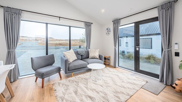 A modern living room with a grey sofa, two armchairs, a small white coffee table, and a large window with grey curtains. - peaceful /warm /family friendly /2bedroom2bathroom/kingbed/unitB (Lake Tekapo)