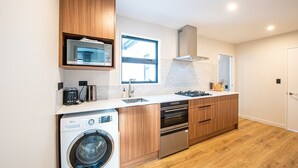 A modern kitchen with wooden cabinets, a built-in microwave, a gas stove, and a washing machine. - peaceful /warm /family friendly /2bedroom2bathroom/kingbed/unitB (Lake Tekapo)