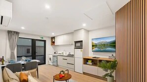 Een moderne woonkamer met een bank, een eettafel en een keukenhoek met een televisie.