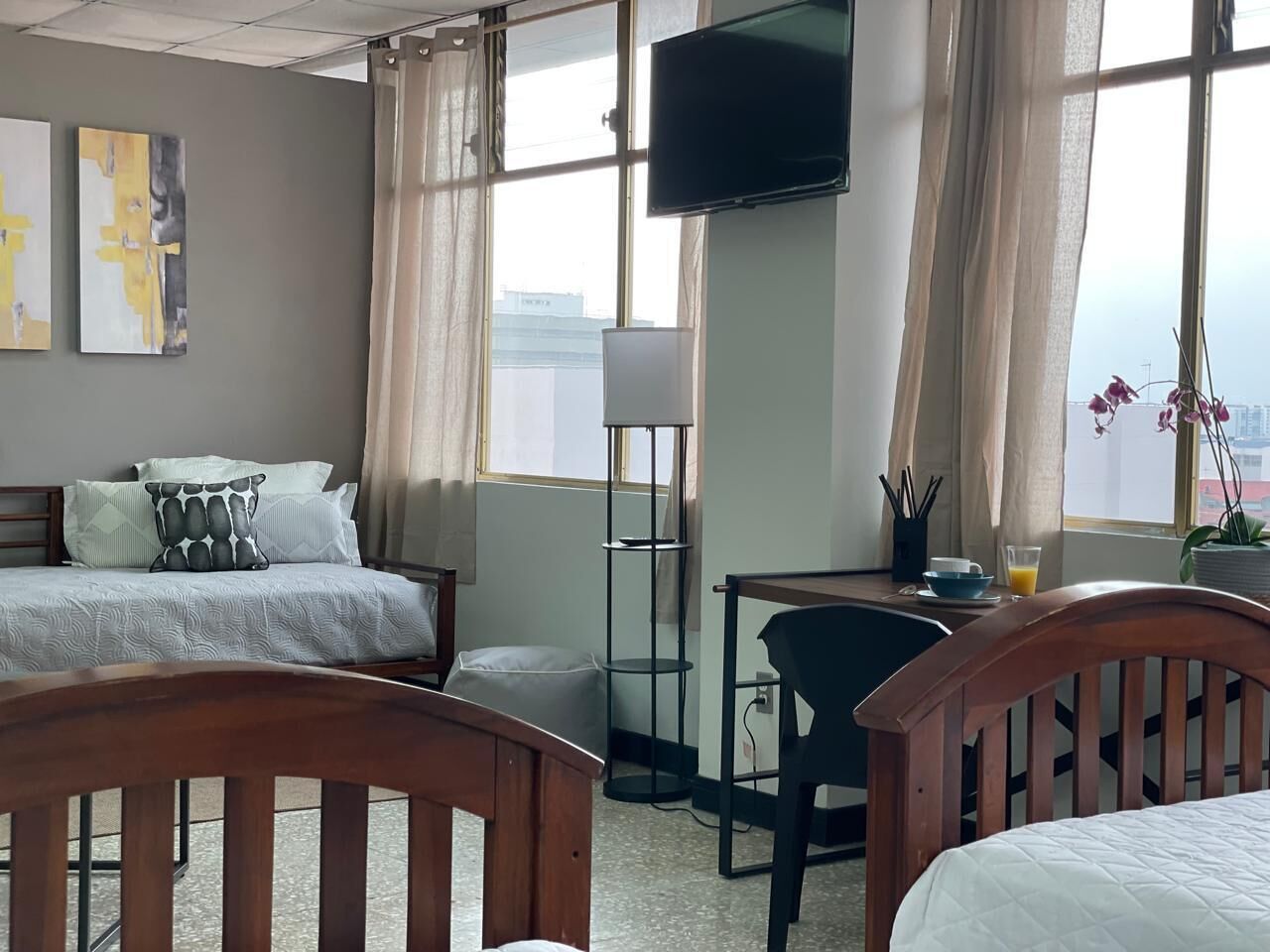 A hotel room with a bed, a desk, a chair, a TV, and a window with curtains.