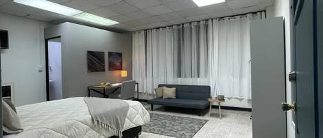 A hotel room with a bed, a sofa, a desk, and a wardrobe.