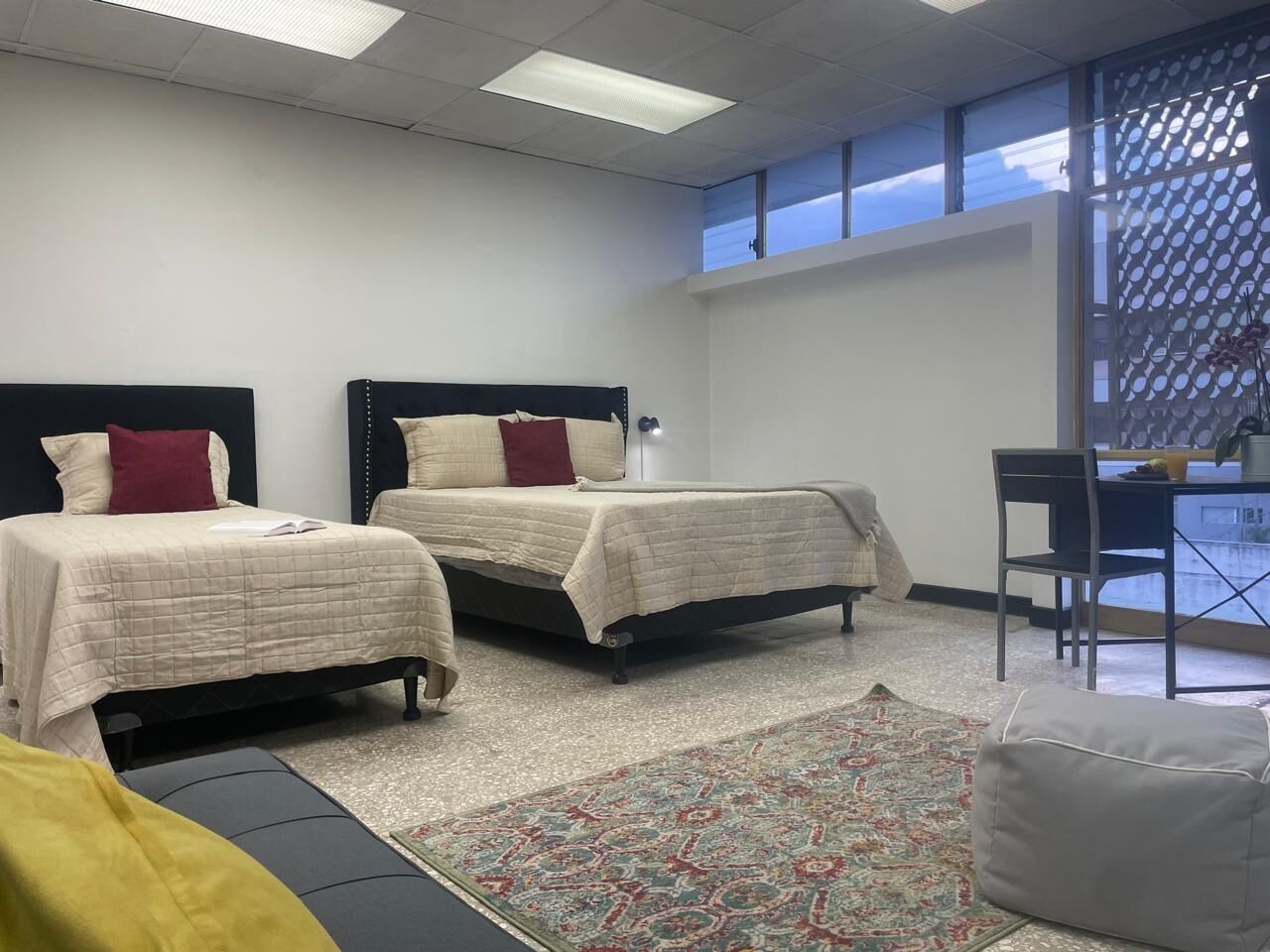 A hotel room with two beds, a desk, and a chair.