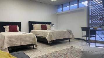 A hotel room with two beds, a desk, and a chair.
