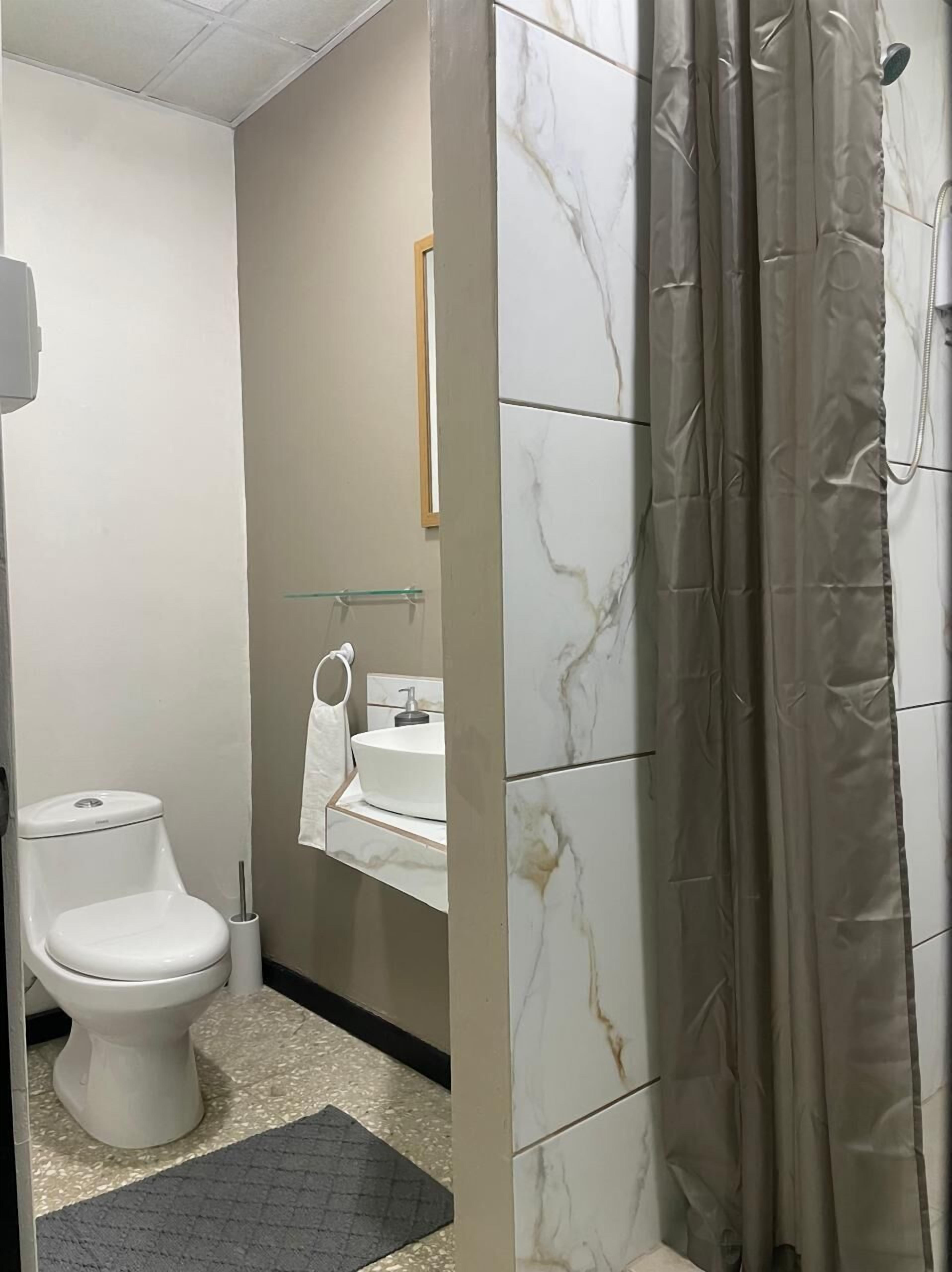 Een badkamer met toilet, wastafel en douchegordijn.