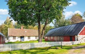 Un cadre rural avec une clôture blanche en bois, une grange rouge et une maison blanche avec un toit en tuiles.
