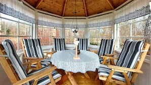 A wooden-paneled room with a round table and six striped chairs.