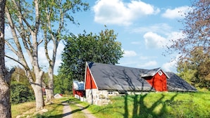 A rural setting with a stone building and a red barn.