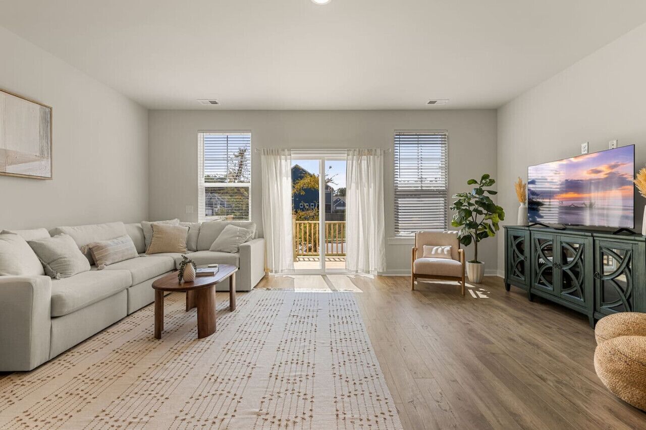A living room with a sofa, coffee table, TV, and a balcony with a view.