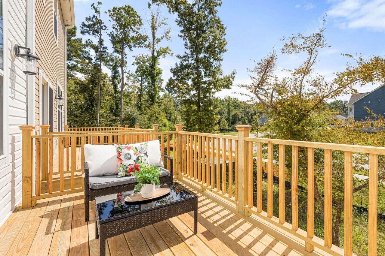 A wooden deck with a sofa and a table, surrounded by a wooden railing.