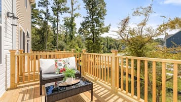 A wooden deck with a sofa and a table, surrounded by a wooden railing.