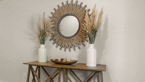 A wooden console table with a mirror, two vases with dried plants, and a bowl of decorative items. - Lux Charleston Residence for 10+ (Hanahan)
