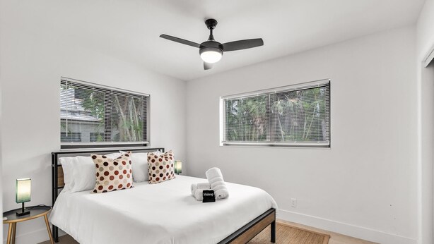 A bedroom with a bed, a nightstand, a lamp, a ceiling fan, and two windows with blinds. - Modern 2/1 rent near Las Olas Fort Lauderdale (Fort Lauderdale)