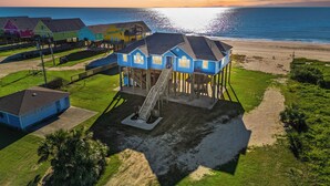 A beachfront property with a house elevated on stilts, a small pool, and a beach in the background. - Spacious Getaway | Gulf Views & Gameroom Fun (Gilchrist)