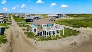 A beachfront property with a large house featuring a balcony and a covered porch. - Beachfront | Direct Access, Outdoor Bar & Grill (Crystal Beach)