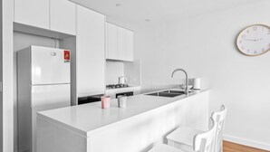 Una cocina moderna con armarios blancos, una isla central, un fregadero y un reloj de pared.
