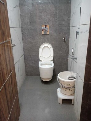 A small bathroom with a toilet, bidet, and a wooden door.