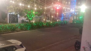 A street at night with string lights and a building with a red and blue illuminated sign. - Gatsby Hotel Jaipur (Jaipur)